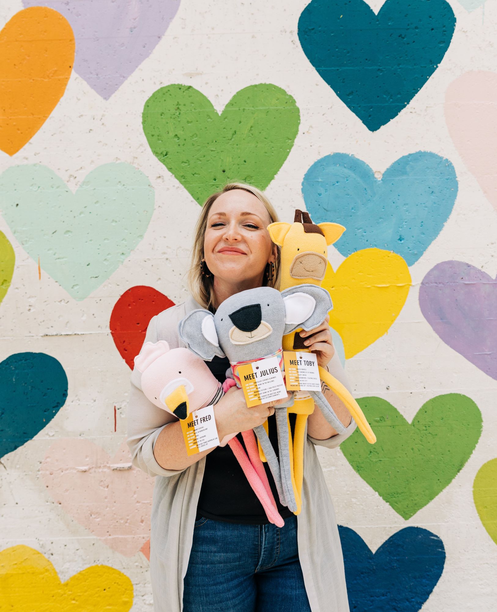 Photo of Kaylyn Van Camp with some of her creations on a background of colorful hearts