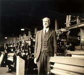 Photograph of Dean Nelson in a room full of looms.