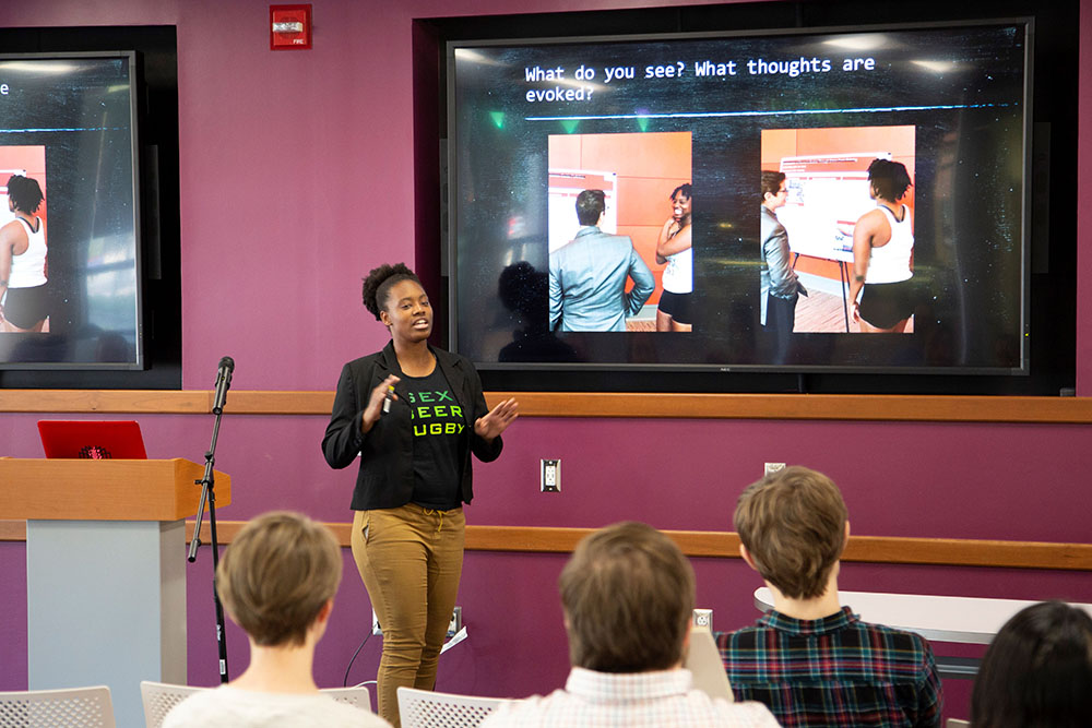 A student in front of a screen, talking to the audiance.