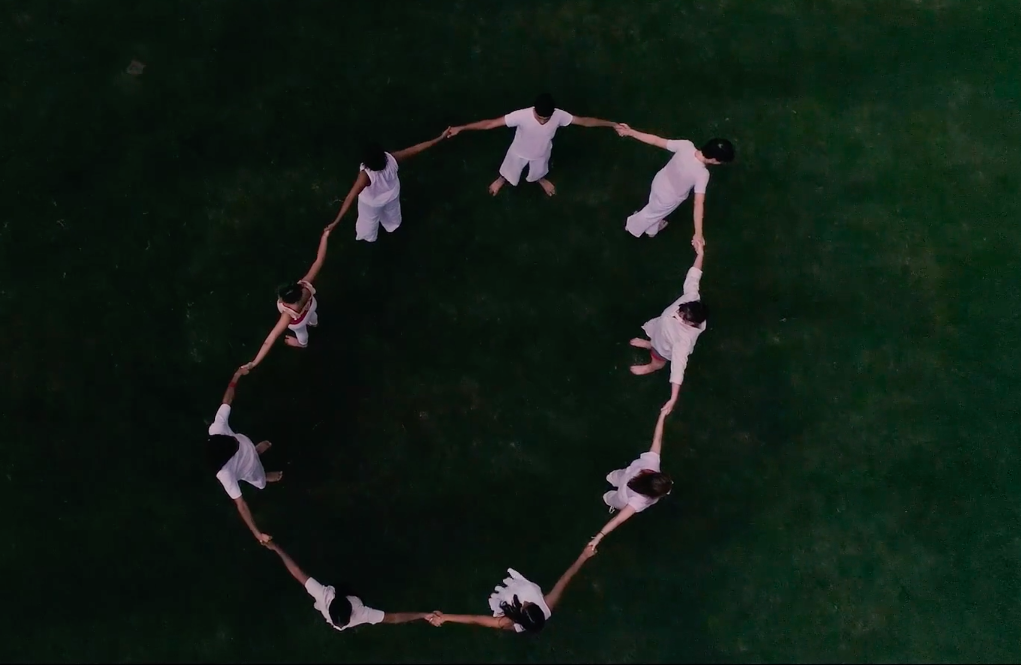 A still image of dancers in a circle, as seen from above, from a dance video by choreographer Killian Manning.
