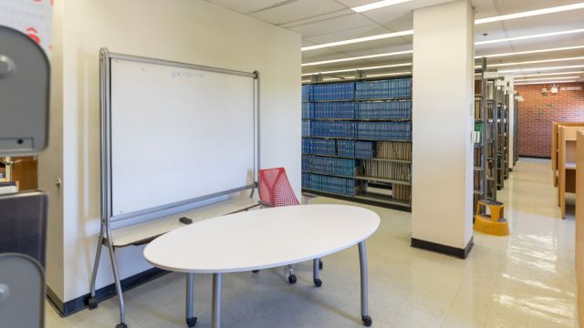 Large table with moveable whiteboard and task chair.